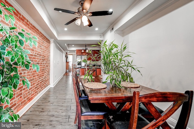 dining room featuring ceiling fan, brick wall, light hardwood / wood-style flooring, and crown molding