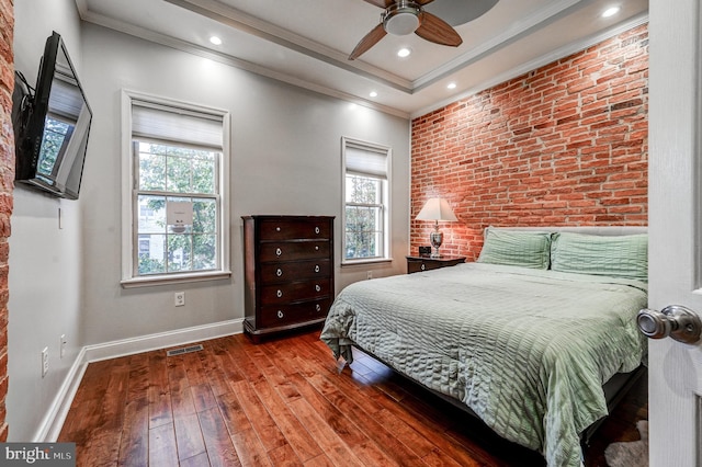 bedroom with multiple windows, wood-type flooring, brick wall, and ceiling fan