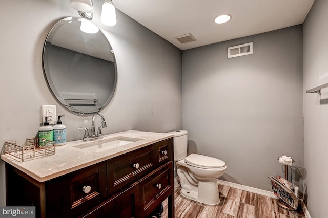 bathroom with toilet, vanity, and wood-type flooring