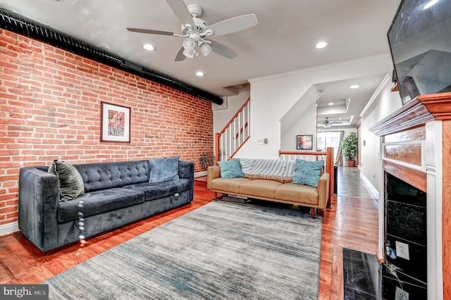 living room featuring ornamental molding, hardwood / wood-style floors, brick wall, and ceiling fan