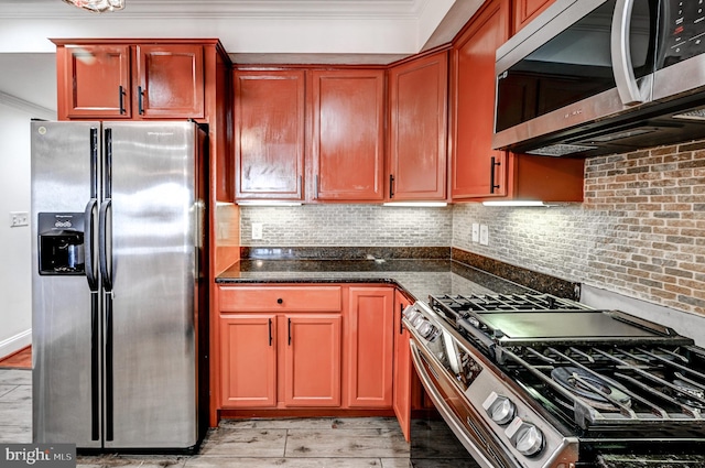 kitchen featuring dark stone counters, tasteful backsplash, light wood-type flooring, and appliances with stainless steel finishes