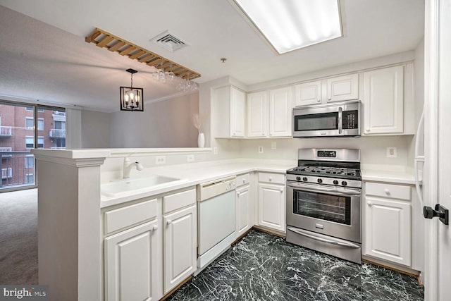 kitchen with kitchen peninsula, appliances with stainless steel finishes, sink, decorative light fixtures, and white cabinetry