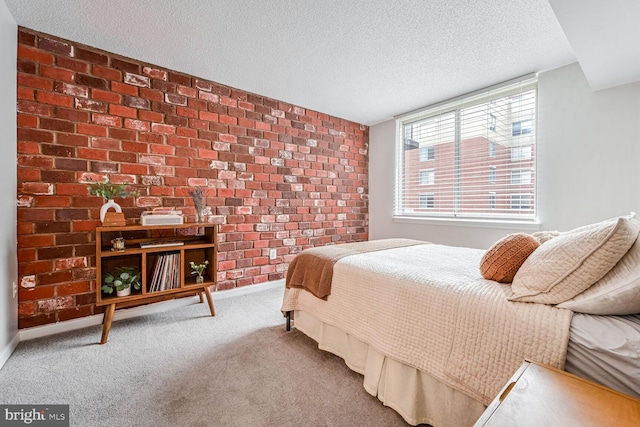 bedroom with carpet flooring, a textured ceiling, and brick wall