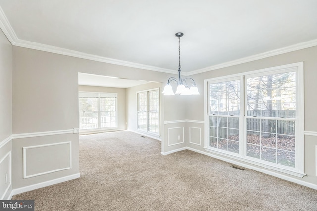 unfurnished dining area featuring carpet floors, a healthy amount of sunlight, crown molding, and an inviting chandelier