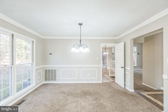 unfurnished room with carpet, a chandelier, and crown molding