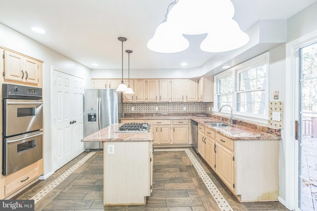 kitchen featuring appliances with stainless steel finishes, sink, a healthy amount of sunlight, and a center island