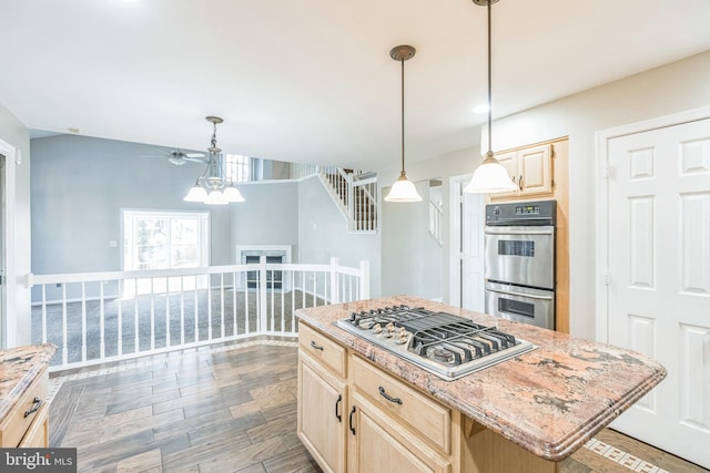 kitchen featuring appliances with stainless steel finishes, dark hardwood / wood-style flooring, light brown cabinetry, pendant lighting, and a center island