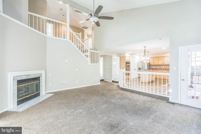 unfurnished living room with a fireplace, a high ceiling, and carpet flooring