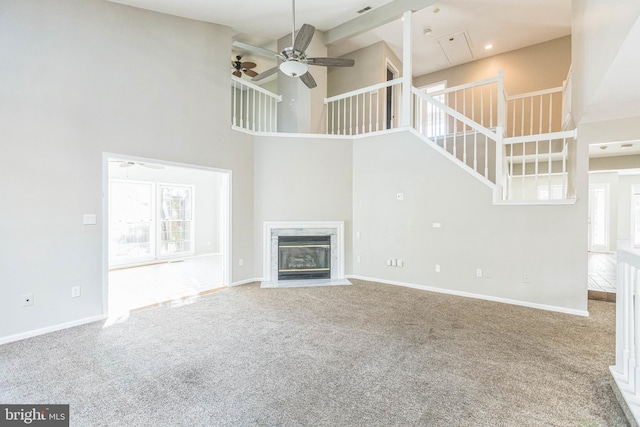 unfurnished living room with carpet flooring, a fireplace, a healthy amount of sunlight, and a high ceiling