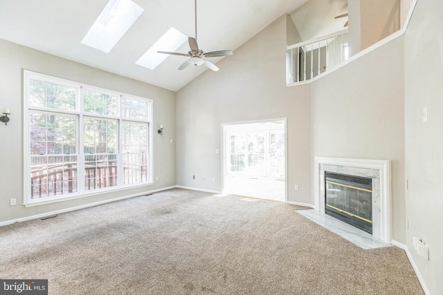 unfurnished living room featuring light carpet, high vaulted ceiling, ceiling fan, a skylight, and a fireplace