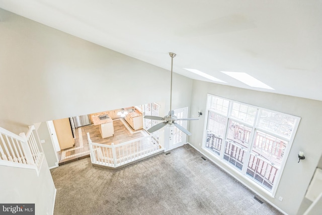 carpeted living room featuring lofted ceiling with skylight and ceiling fan