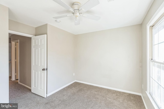 carpeted spare room featuring ceiling fan