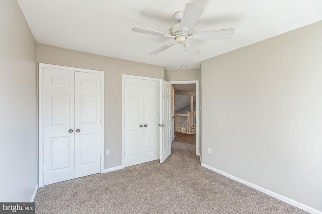 unfurnished bedroom with multiple closets, light colored carpet, and ceiling fan