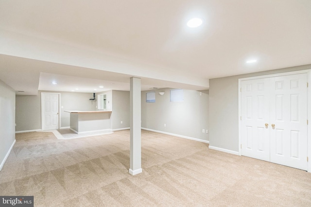 basement with bar and light colored carpet