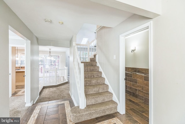 stairway with an inviting chandelier and carpet floors