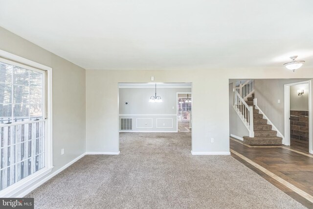 unfurnished living room with a chandelier and carpet