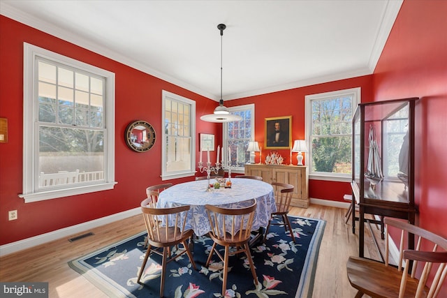 dining room featuring light hardwood / wood-style flooring, crown molding, and plenty of natural light