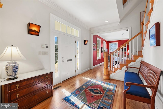 entrance foyer featuring ornamental molding and light hardwood / wood-style floors