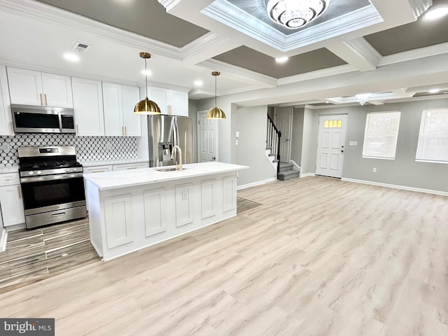 kitchen with appliances with stainless steel finishes, light wood-type flooring, a center island with sink, and white cabinetry