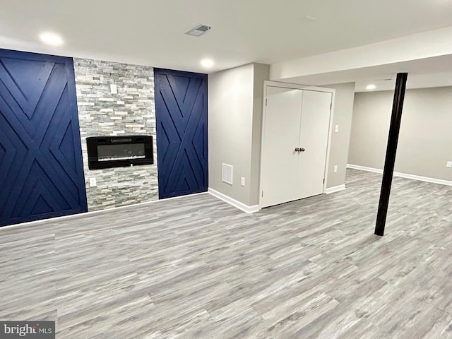 basement with a large fireplace and light wood-type flooring