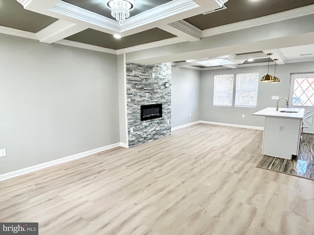 unfurnished living room with light wood-type flooring, coffered ceiling, crown molding, sink, and a fireplace