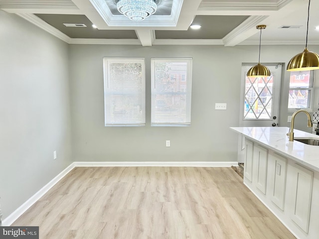 kitchen featuring sink, hanging light fixtures, light stone countertops, ornamental molding, and white cabinetry