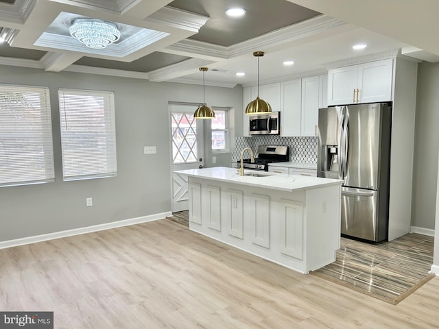 kitchen with light wood-type flooring, stainless steel appliances, decorative light fixtures, a center island with sink, and white cabinetry