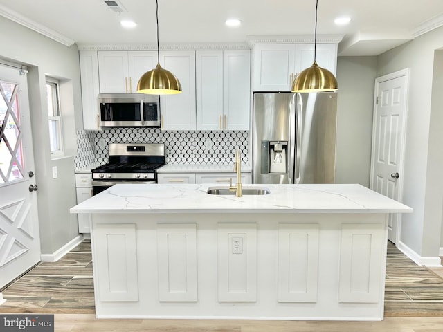 kitchen featuring light stone countertops, appliances with stainless steel finishes, white cabinetry, and a kitchen island with sink