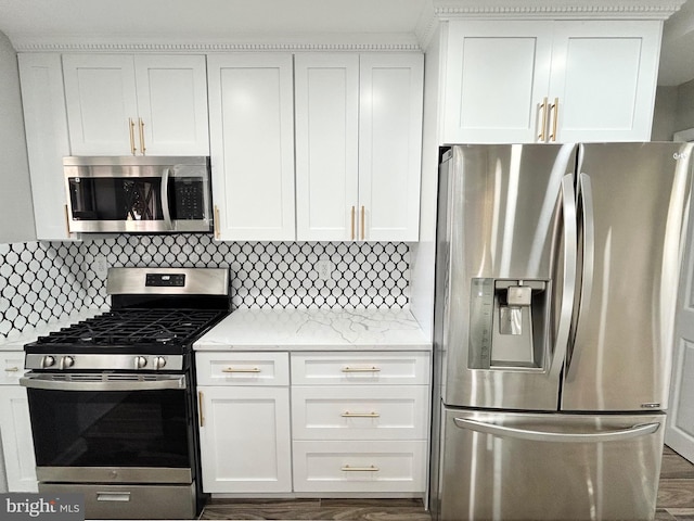 kitchen featuring white cabinets, light stone counters, backsplash, and appliances with stainless steel finishes