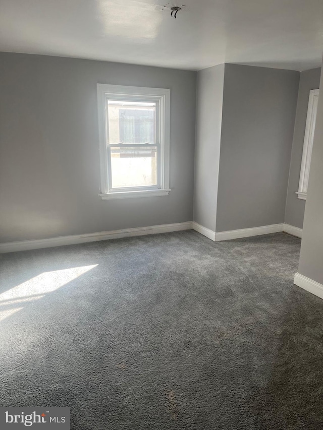 spare room with dark colored carpet