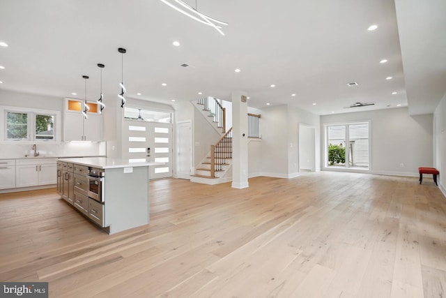 kitchen featuring hanging light fixtures, light wood-type flooring, plenty of natural light, and stainless steel oven