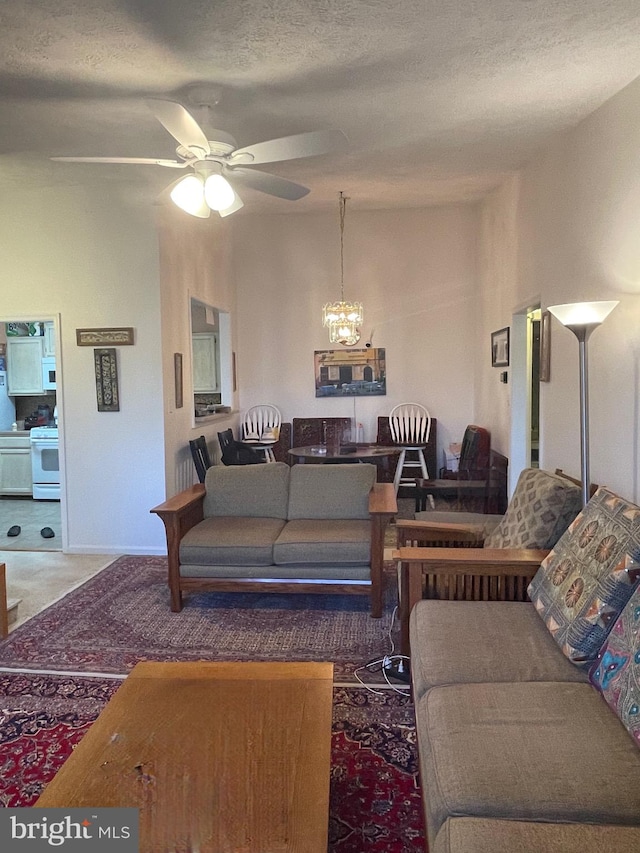 carpeted living room featuring a textured ceiling and ceiling fan with notable chandelier