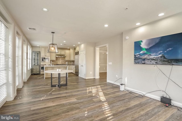 kitchen with a kitchen bar, backsplash, pendant lighting, wood-type flooring, and a kitchen island