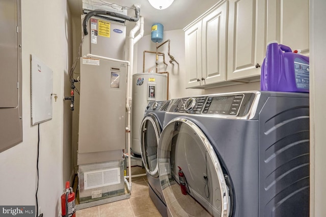 laundry area with cabinets, light tile patterned floors, and washer and clothes dryer