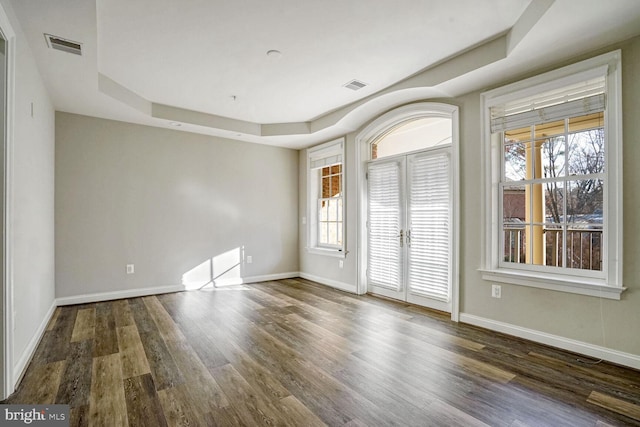 spare room featuring french doors, dark hardwood / wood-style floors, and a tray ceiling