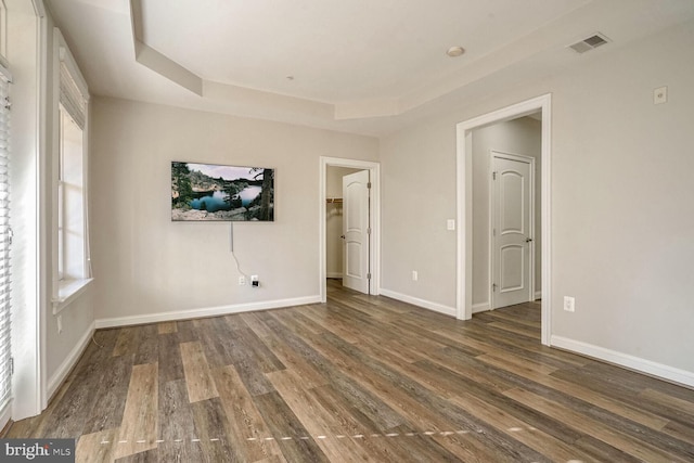 spare room with dark wood-type flooring and a tray ceiling