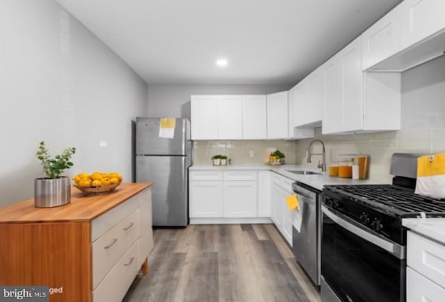 kitchen with backsplash, white cabinets, sink, dark hardwood / wood-style floors, and appliances with stainless steel finishes