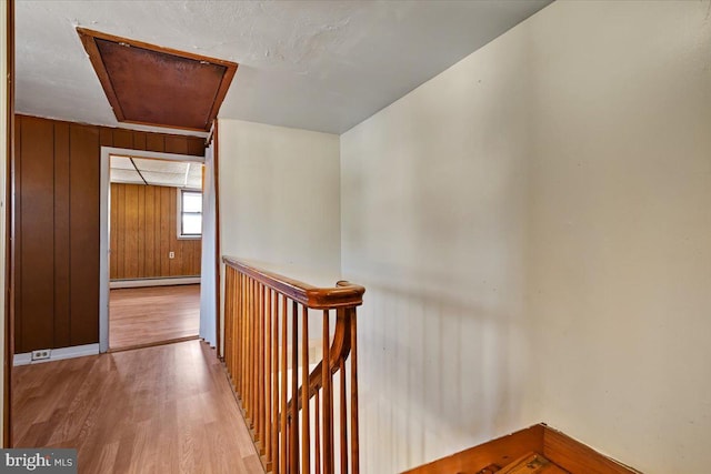 hallway featuring wood walls, a baseboard radiator, and light wood-type flooring