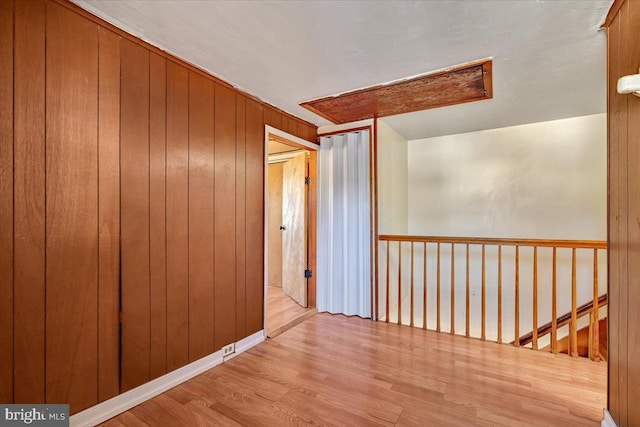 hall with wood walls and light hardwood / wood-style flooring