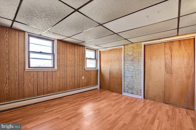 unfurnished bedroom with wood walls, wood-type flooring, and multiple windows