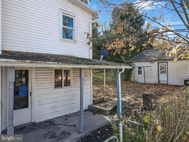 view of property exterior with an outdoor structure and a patio area