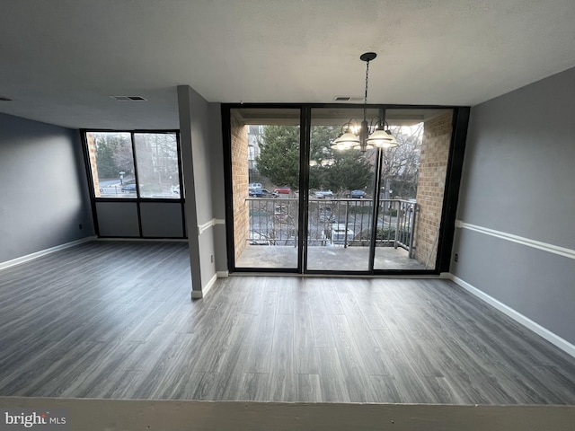 unfurnished dining area with wood-type flooring, a wall of windows, and a notable chandelier