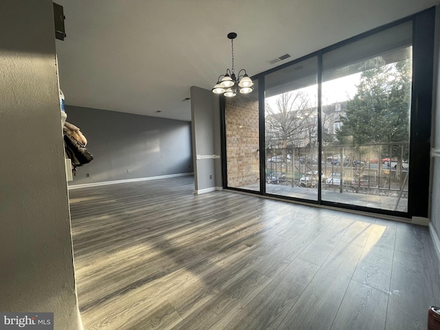 unfurnished dining area featuring a chandelier, hardwood / wood-style floors, and expansive windows