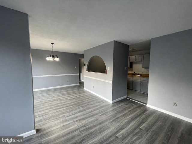 unfurnished living room with a chandelier, dark hardwood / wood-style flooring, and sink