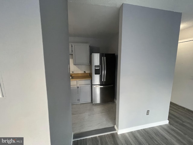 kitchen with dark wood-type flooring, stainless steel refrigerator with ice dispenser, and tasteful backsplash