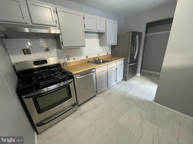 kitchen featuring butcher block counters, gray cabinetry, sink, tasteful backsplash, and appliances with stainless steel finishes