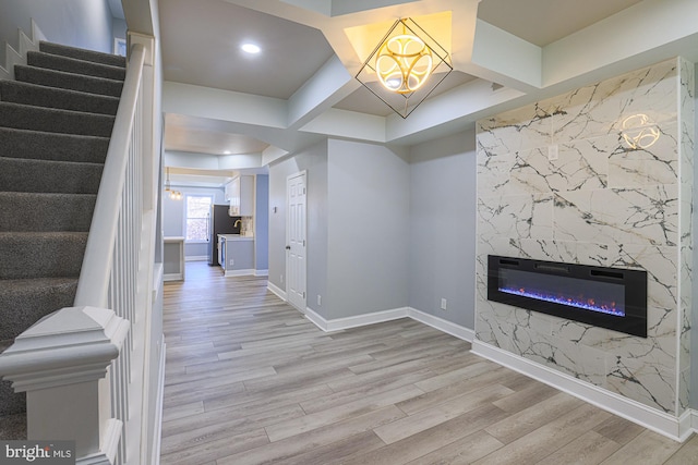 interior space with a fireplace, beamed ceiling, light wood-type flooring, and coffered ceiling