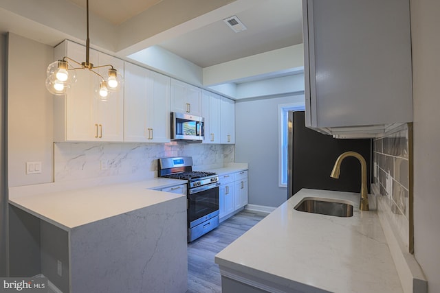 kitchen with white cabinetry, sink, stainless steel appliances, and decorative light fixtures