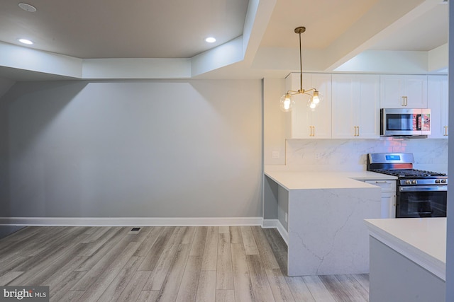 kitchen with backsplash, stainless steel appliances, decorative light fixtures, white cabinets, and light hardwood / wood-style floors