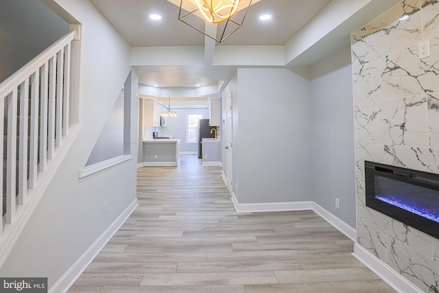 hall featuring sink, light wood-type flooring, and a notable chandelier